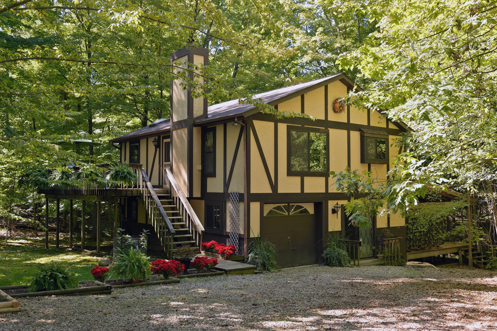 guest cottage from side with shaded trees and red flowers in garden