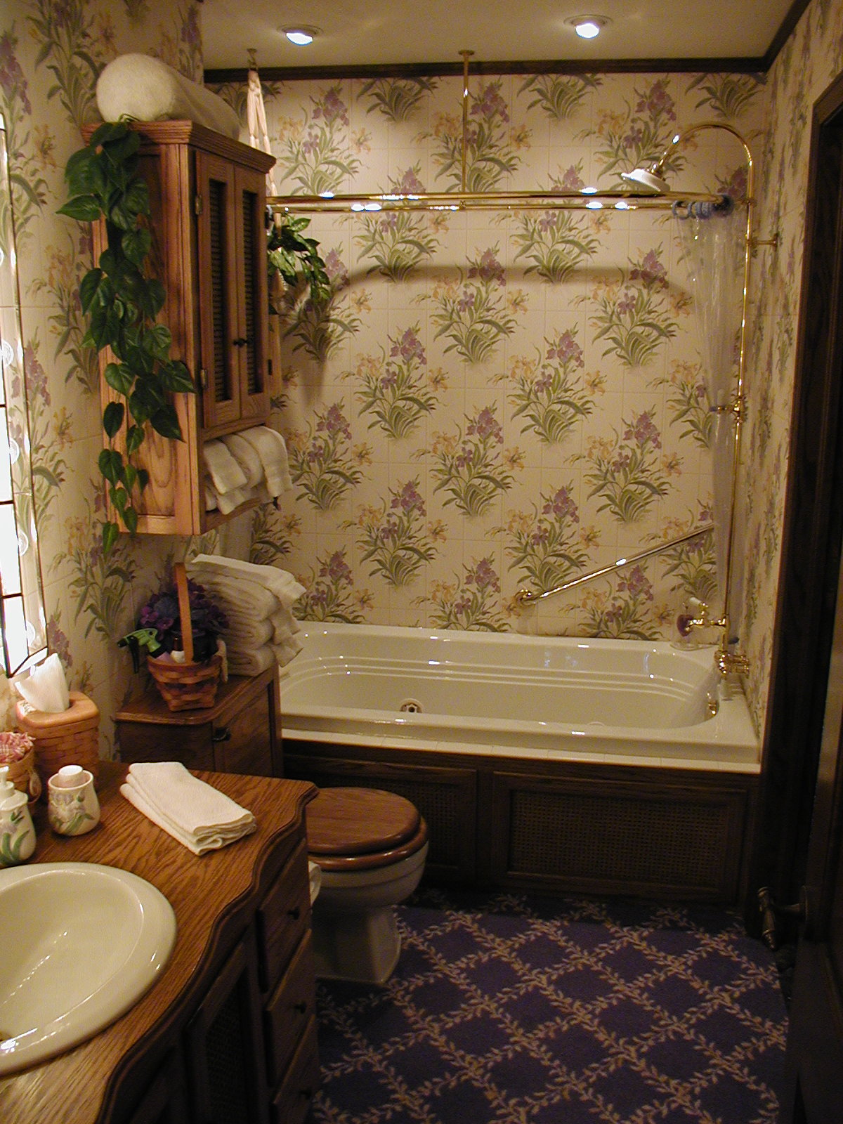 Bathroom with wood countertop, toliet next to bathtub and brass shower