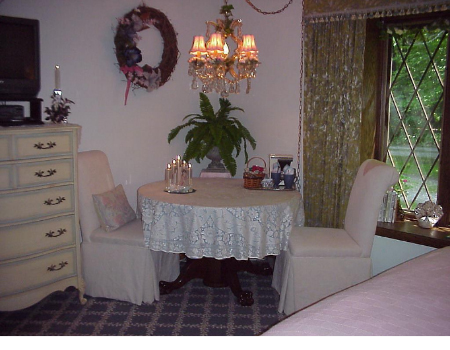 chandlier over sitting area next to tudor glass windows in bedroom